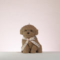 Brown poodle dog-shaped candle with a white ribbon on a light background