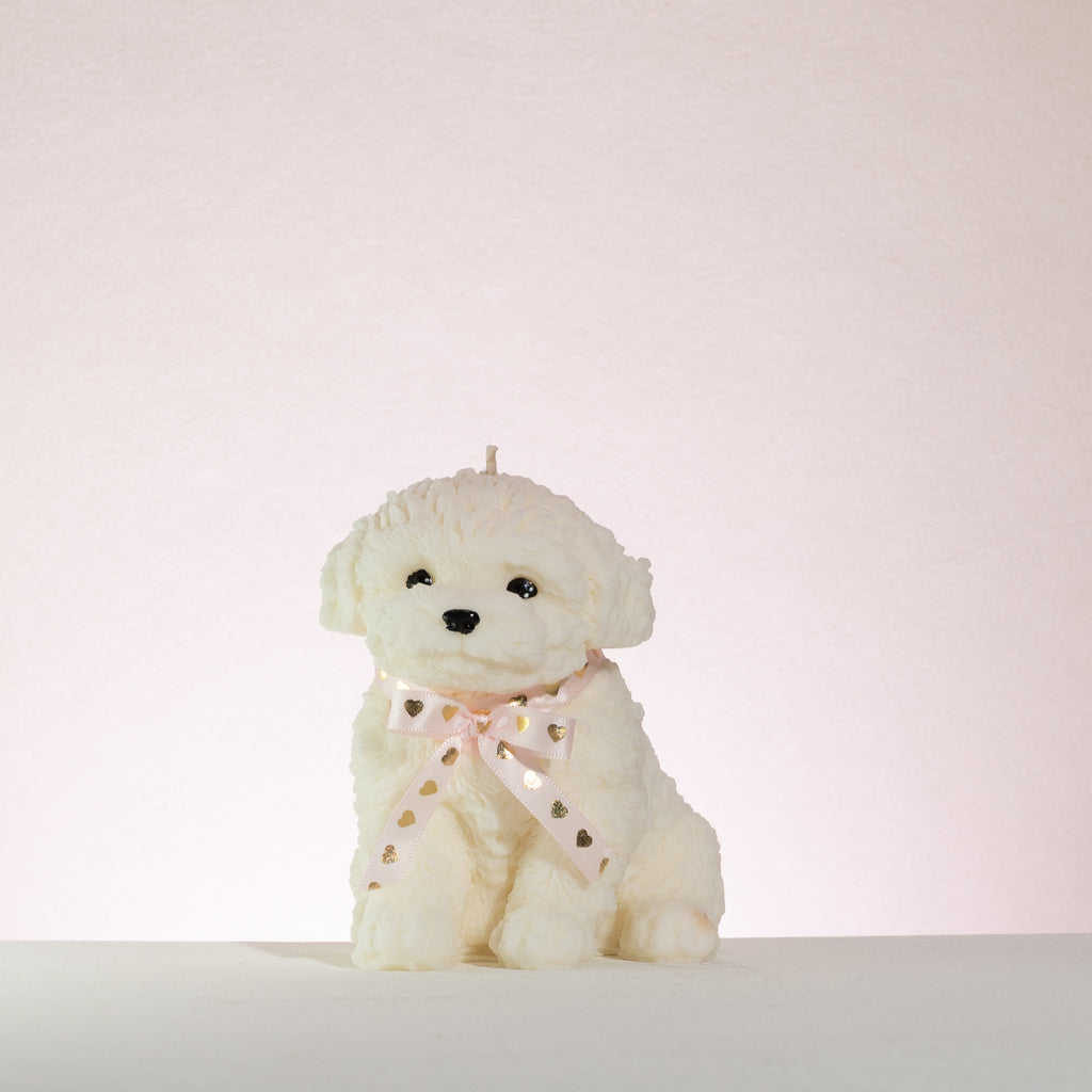 White poodle dog candle with a pink bow on a light pink background