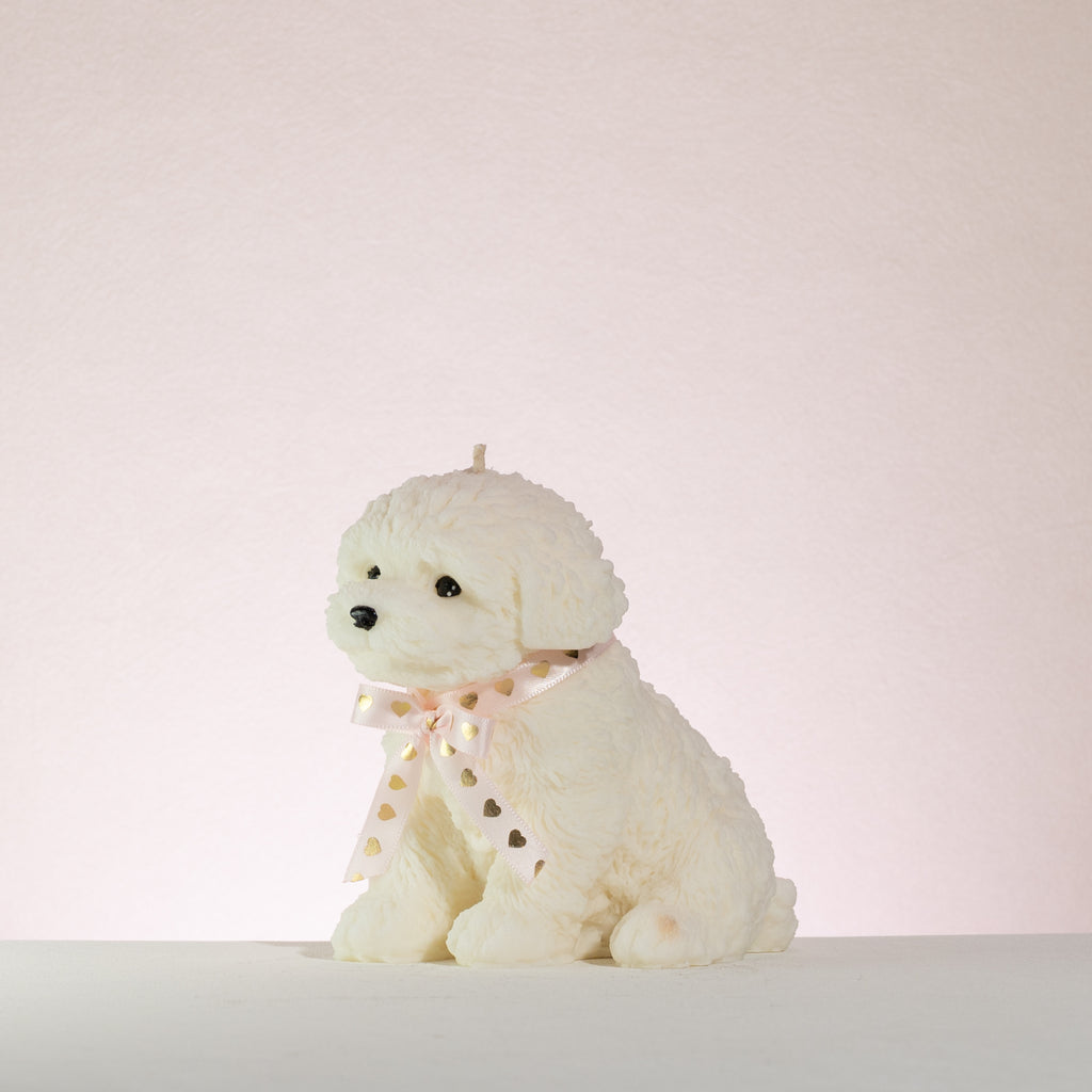 White poodle dog-shaped candle with a pink bow on a light pink background