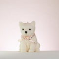 White westie dog-shaped candle with a pink bow on a white background