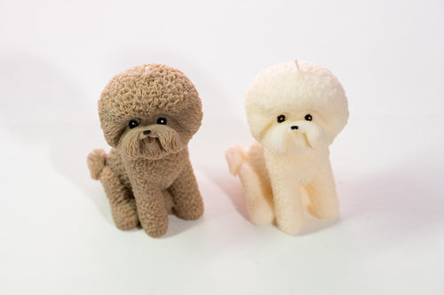 Two small dog figurines, one brown and one cream, on a white background