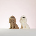 Two cocker spaniel dog-shaped candles, one brown and one white, on a light background